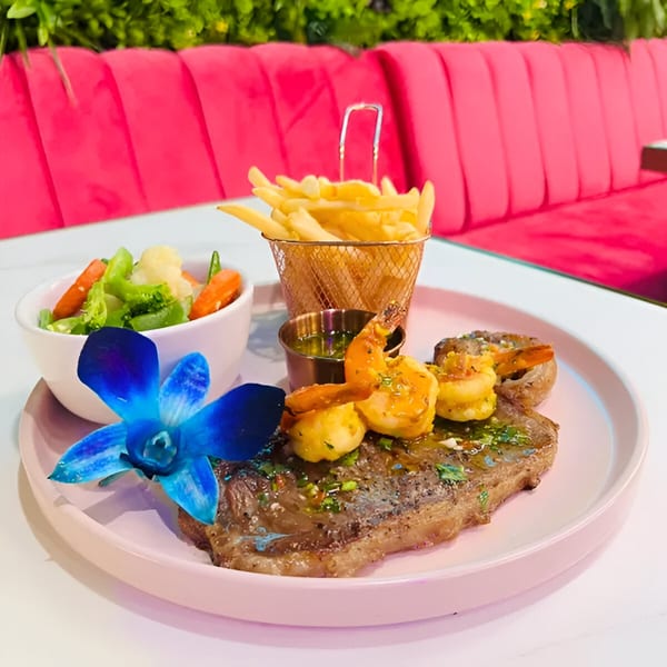 Magic Restaurant's steak and shrimp entree with fries, vegetables, and a blue orchid garnish.