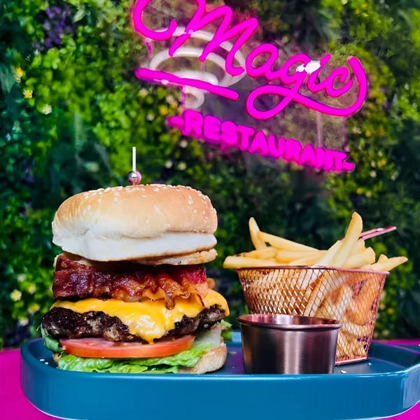 A Magic Restaurant bacon cheeseburger with fries and dipping sauce on a blue tray.